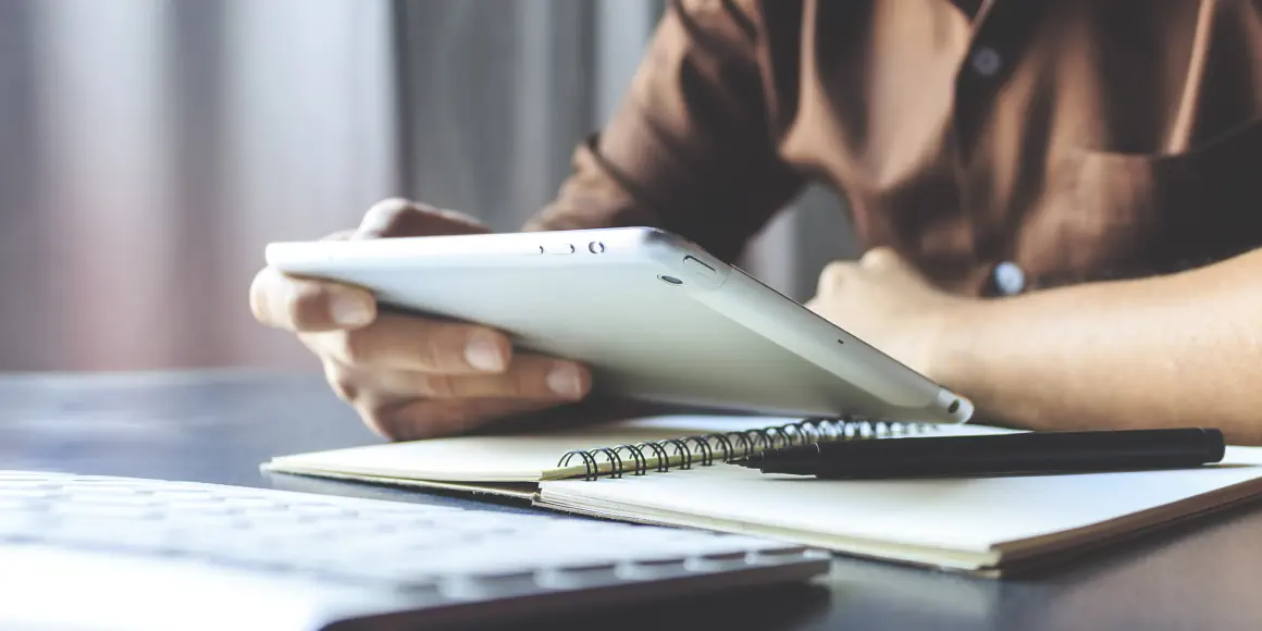 Junger Mann lernt online mit seinem Tablet und macht sich Notizen