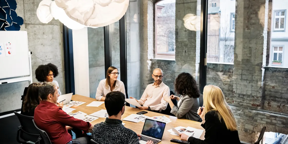 Team Meeting mit zahlreichen Unterlagen auf dem Tagungstisch